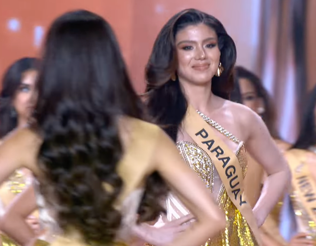 Miss Paraguay walks toward the stage while Miss Panama walks back after viral mishap