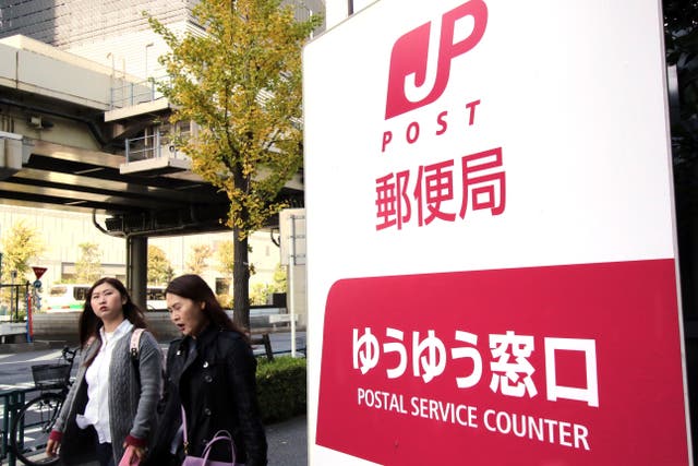 <p>File. Pedestrians walk past a Japan Post office in Tokyo</p>