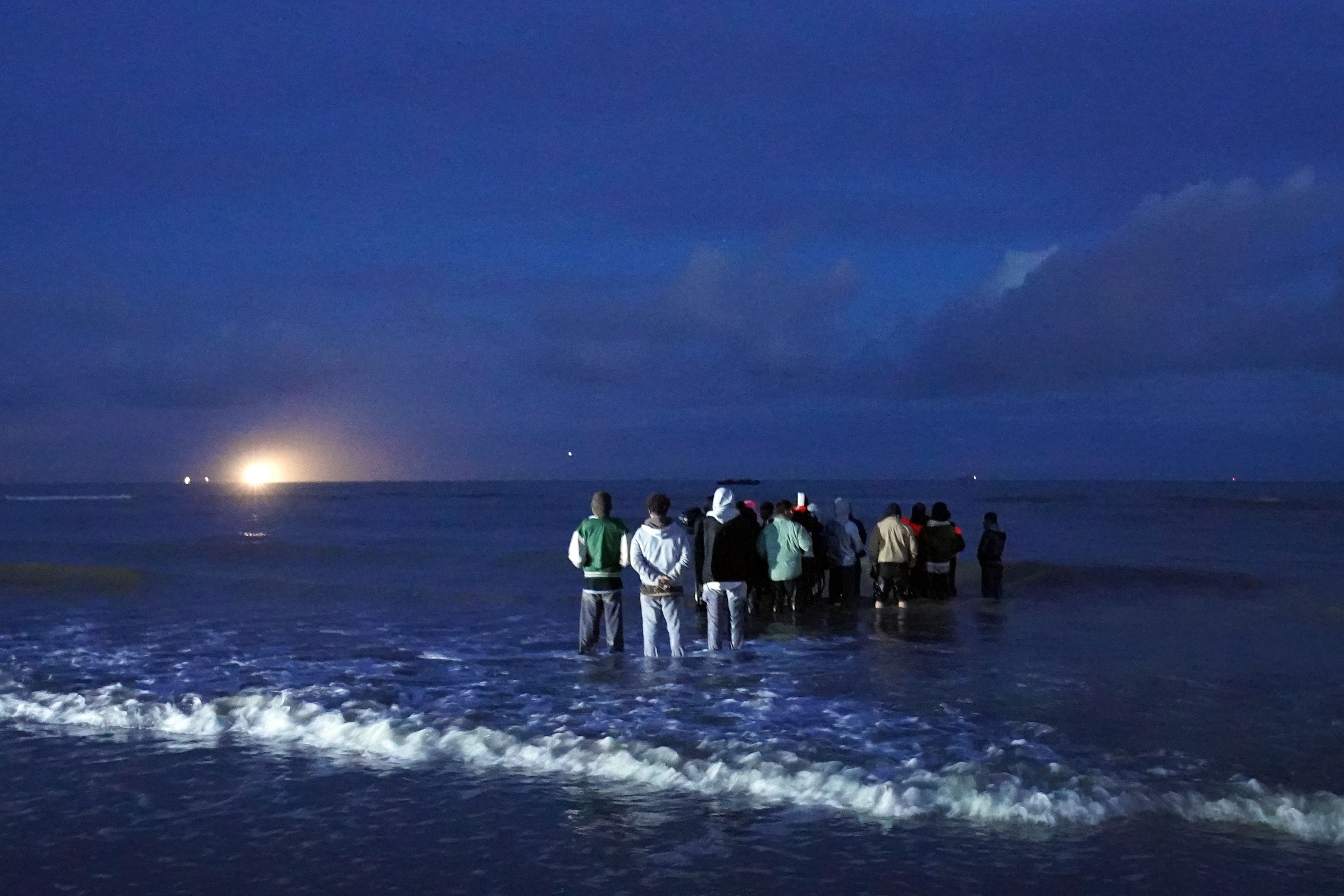People thought to be migrants wait in the darkness to board a small boat in Gravelines, France (Gareth Fuller/PA)