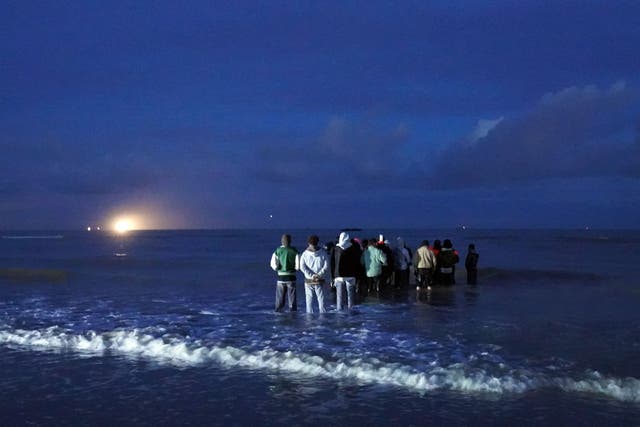 People thought to be migrants wait in the darkness to board a small boat in Gravelines, France (Gareth Fuller/PA)