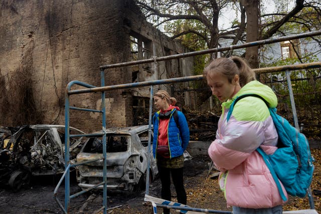 <p>Women stand near burnt-out cars following a drone attack in Kyiv, on October 23, 2025, amid the Russian invasion of Ukraine</p>