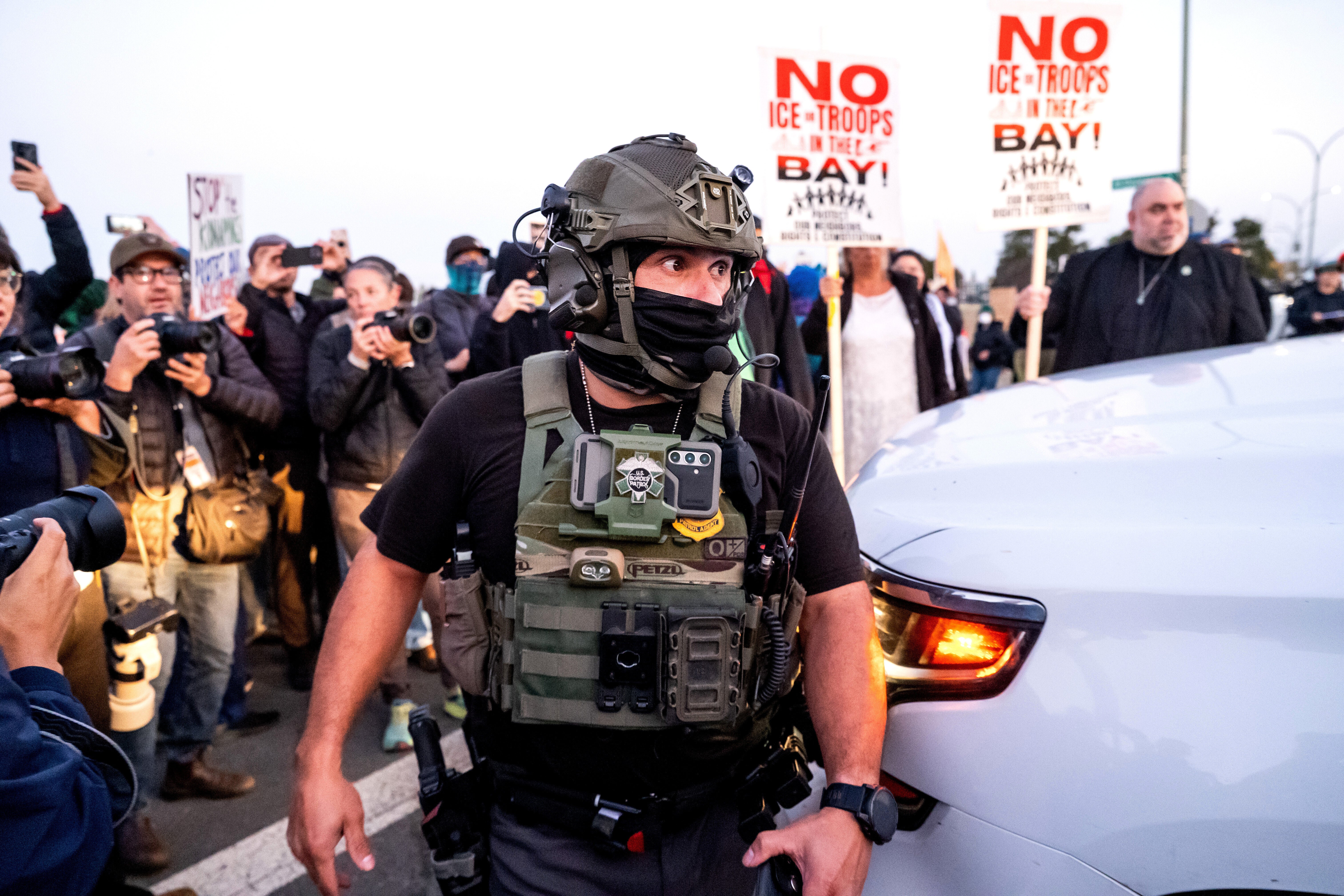 A U.S. Border Patrol officer tries to clear protesters while entering the Coast Guard base near San Francisco. where roughly 100 federal agents reportedly arrived on Wednesday or Thursday for Trump’s ‘surge’