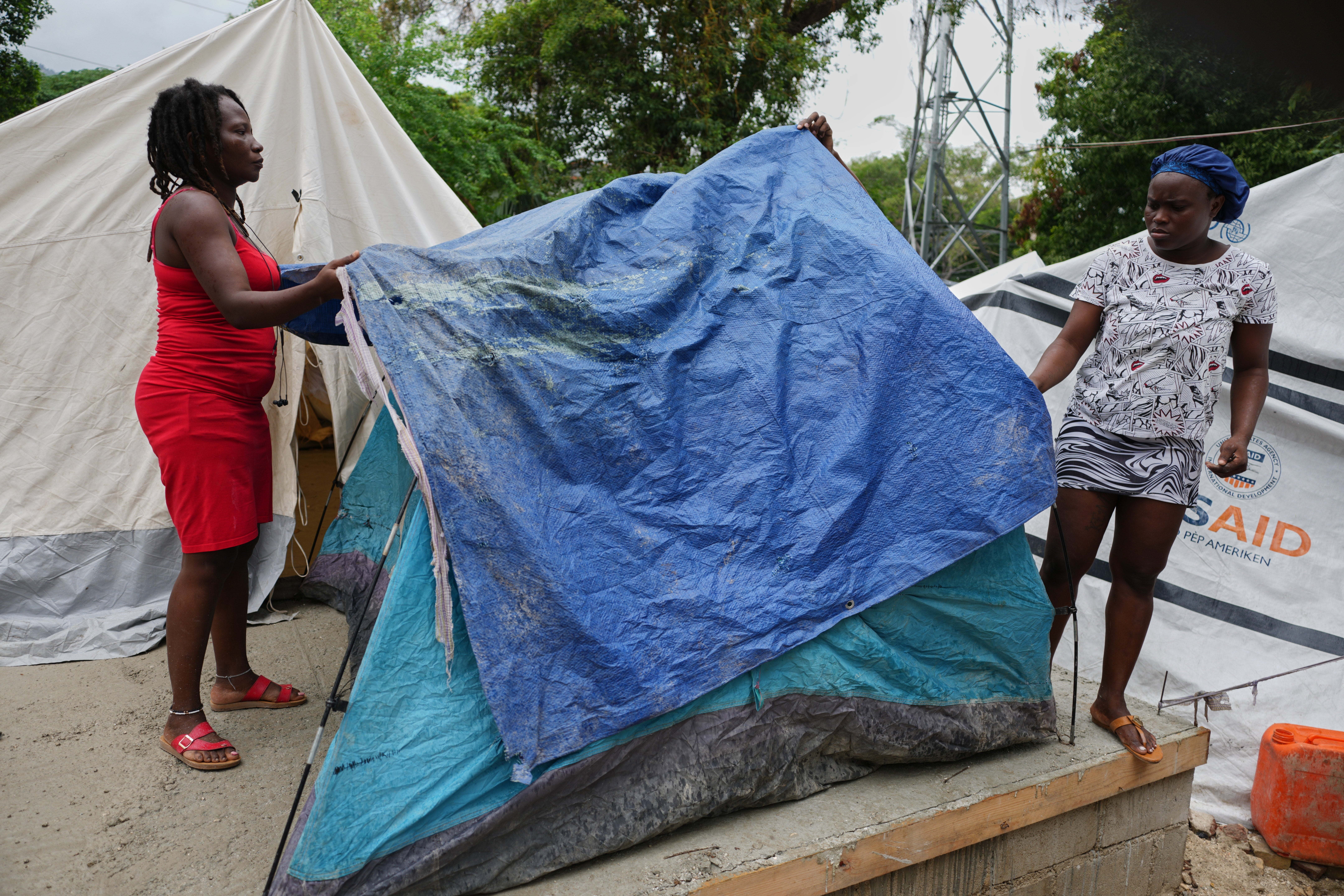 Pessoas colocam lonas plásticas em suas barracas antes da chuva esperada em um abrigo para famílias deslocadas pela violência de gangues em Porto Príncipe, Haiti.