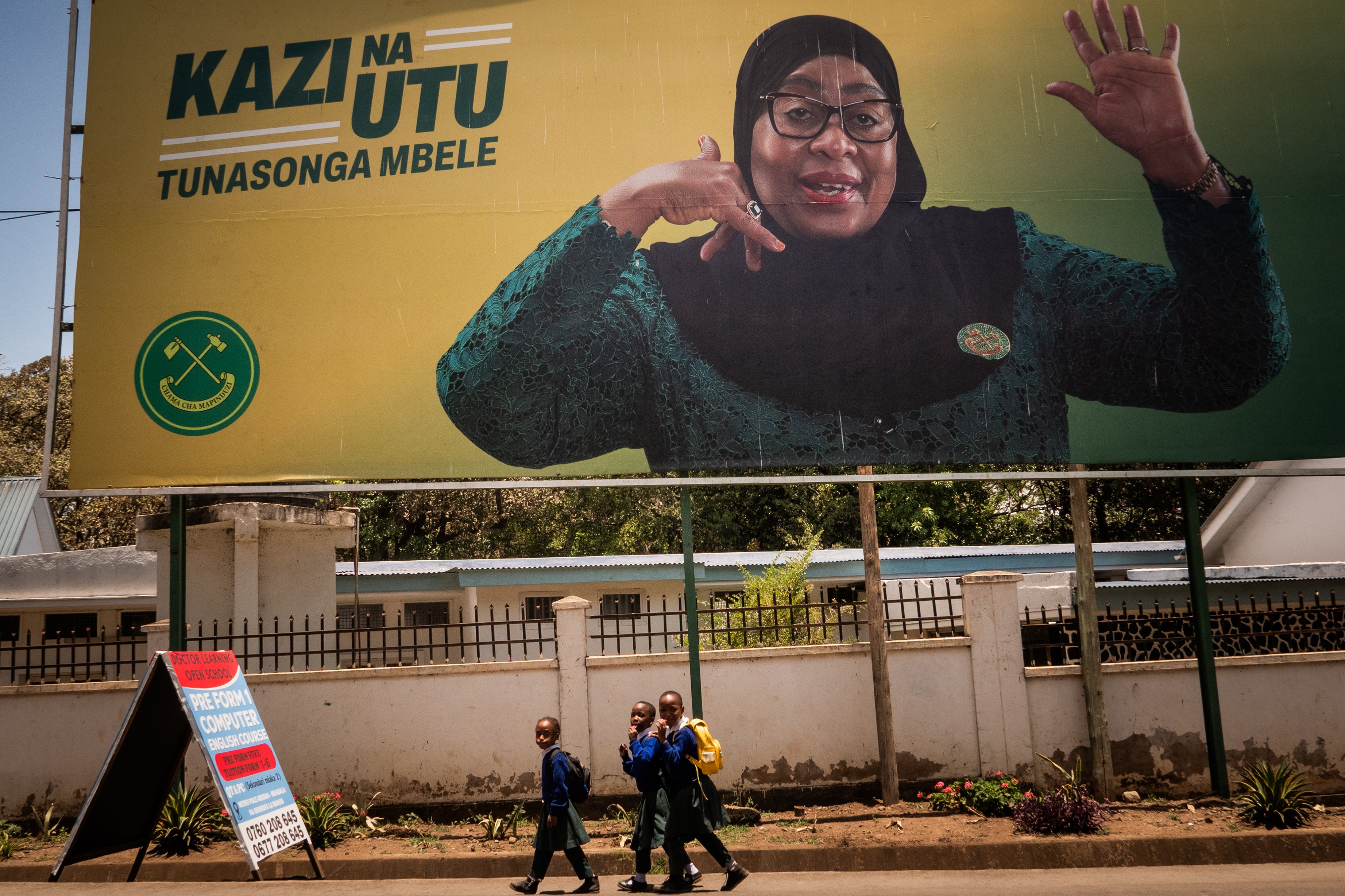 <p>Children walk past a billboard for Tanzanian presidential candidate Samia Suluhu Hassan</p>