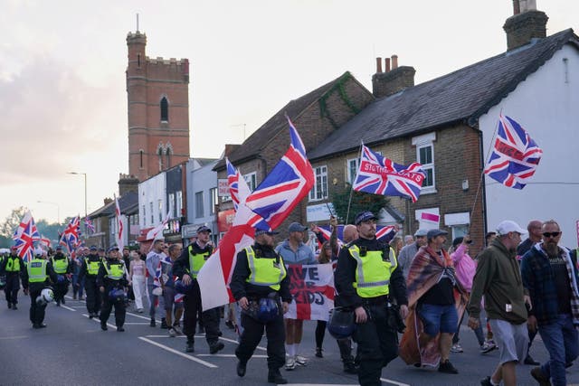 <p>Police officers escort protesters near the Bell Hotel in Epping in August after a temporary injunction that would have blocked asylum seekers from being housed at the hotel was overturned</p>