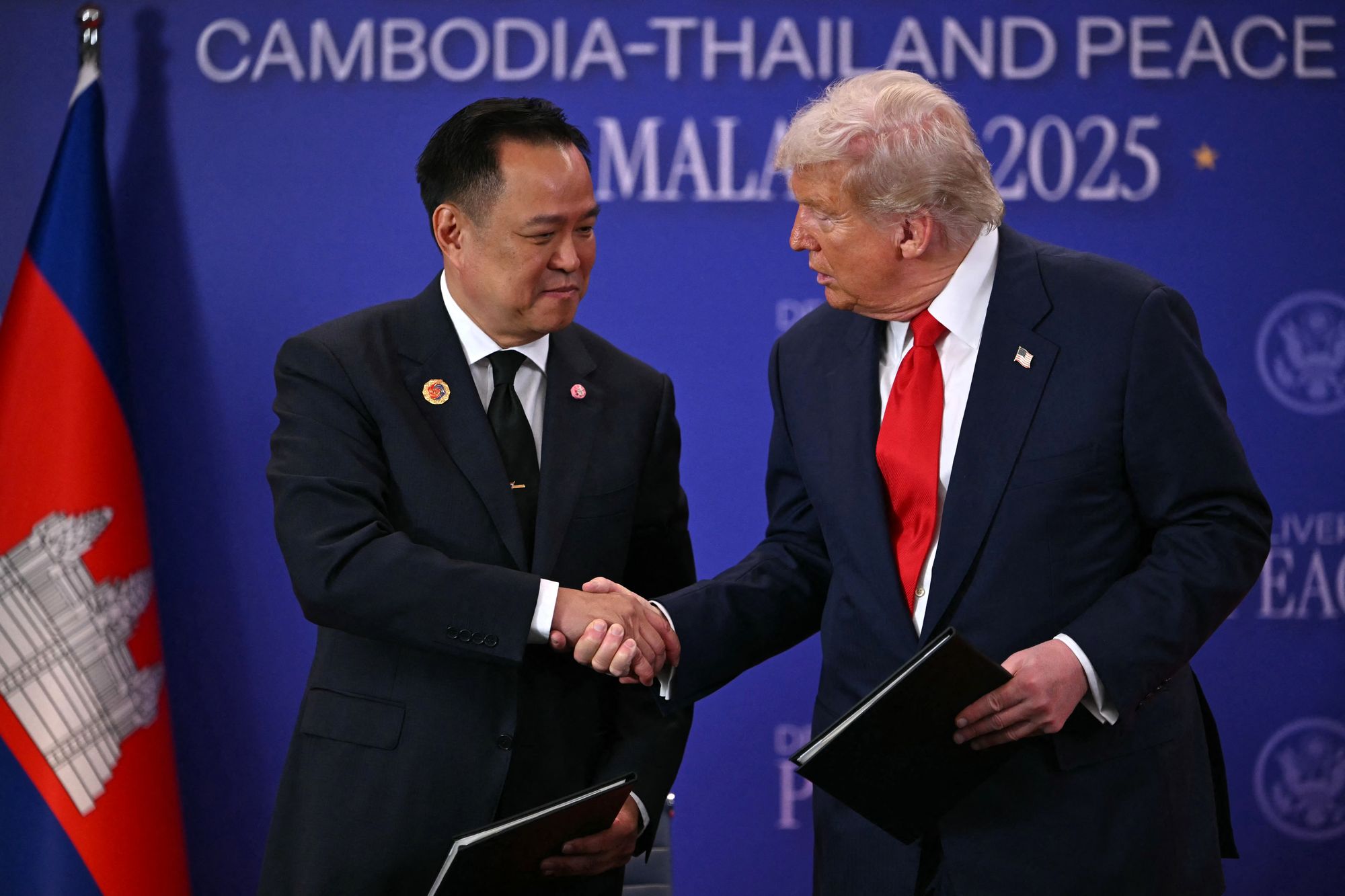 US President Donald Trump (R) shakes hands with Thailand's Prime Minister Anutin Charnvirakul during the ceremonial signing of a ceasefire agreement between Thailand and Cambodia