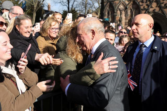 The King is embraced by a member of the public as he arrives at Lichfield Cathedral (Temilade Adelaja/PA)