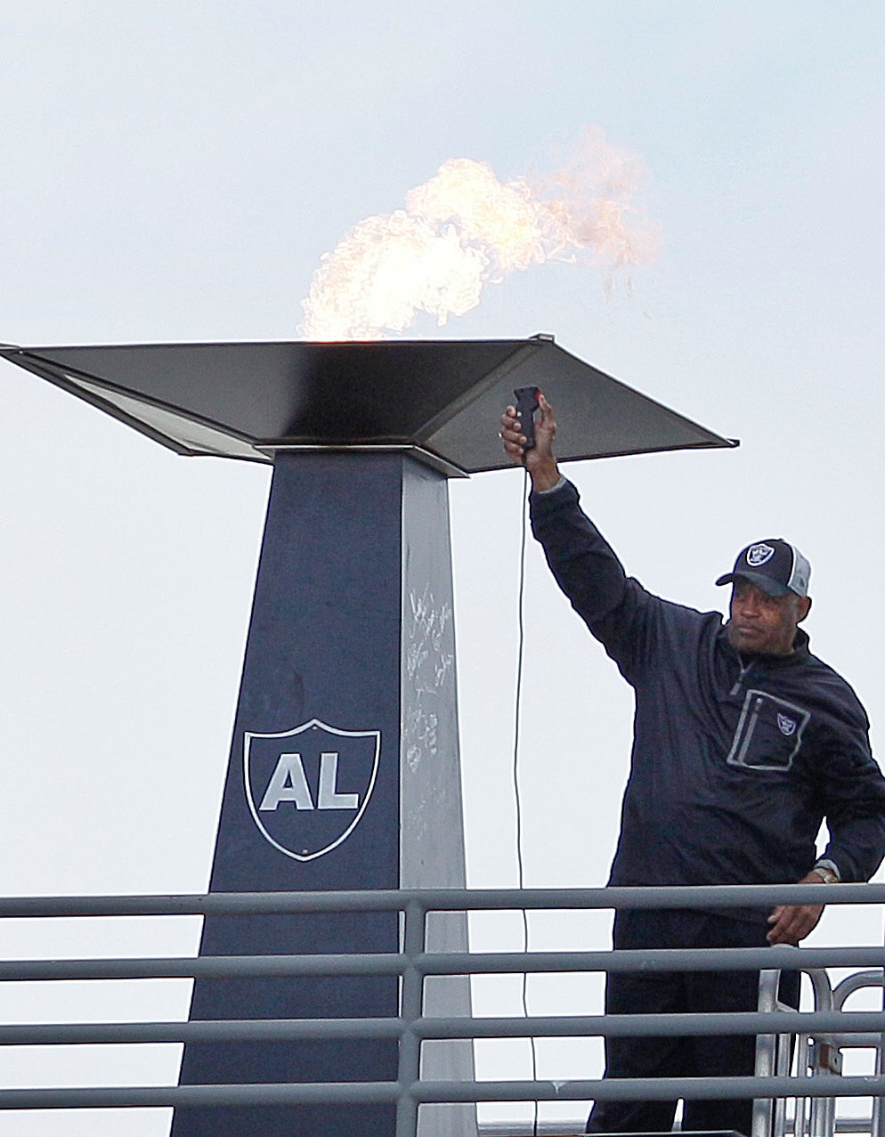 El ex jugador de los Oakland Raiders, George Atkinson, saluda después de encender una antorcha para el ex propietario de los Raiders, Al Davis, antes de un partido de fútbol americano de la NFL entre los Oakland Raiders y los Jacksonville Jaguars en Oakland, California, el 21 de octubre de 2012. (Foto AP/Jeff Chiu, archivo)