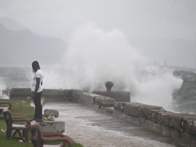 <p>A man watches the waves crash into the walls at the Kingston Waterfront on Monday</p>