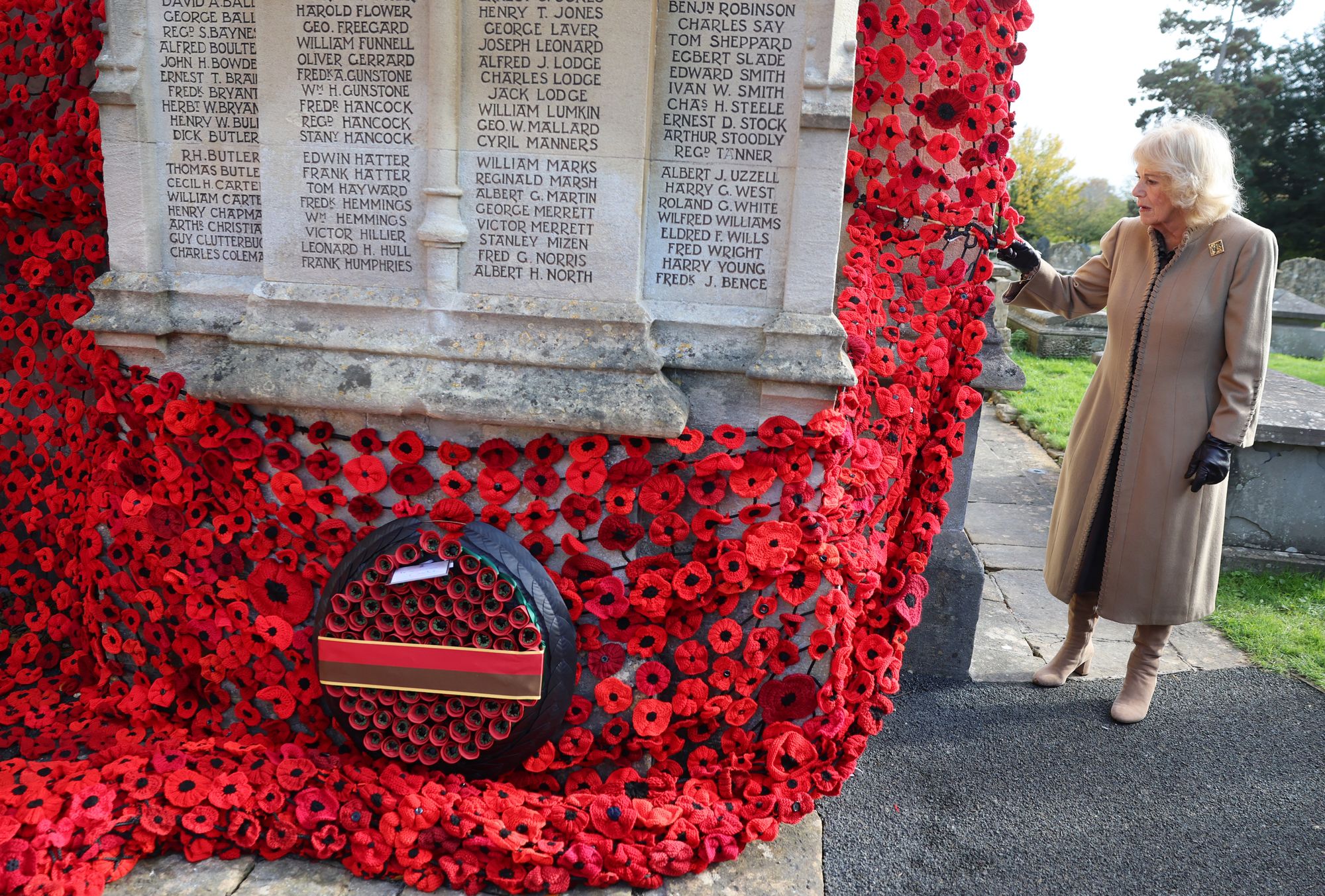 <p>Queen Camilla attaches the final poppy to complete the cascade of 10,000 poppies draping the church tower at St. Bartholomew's Church</p>