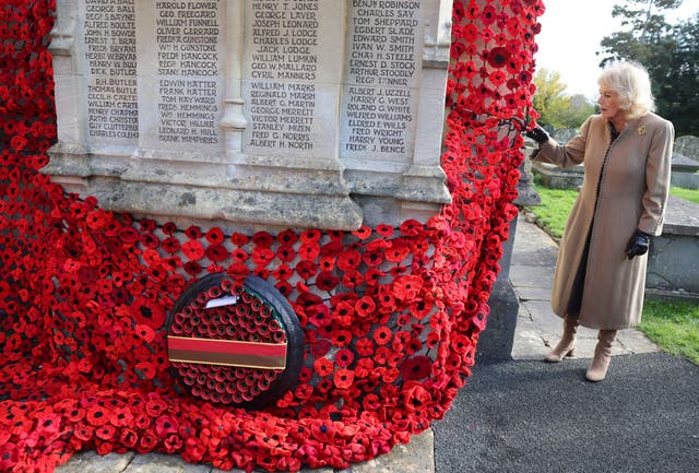 <p>Queen Camilla attaches the final poppy to complete the cascade of 10,000 poppies draping the church tower at St. Bartholomew's Church</p>
