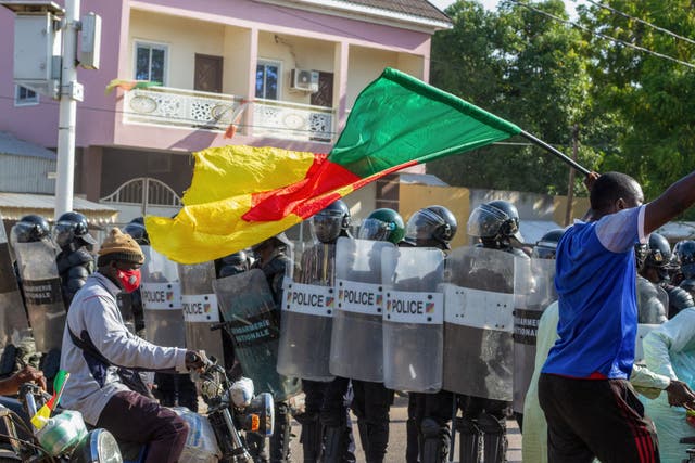 <p>A protester waving a Cameroonian flag approaches Cameroonian police officers as they gather in Garoua on October 26, 2025</p>