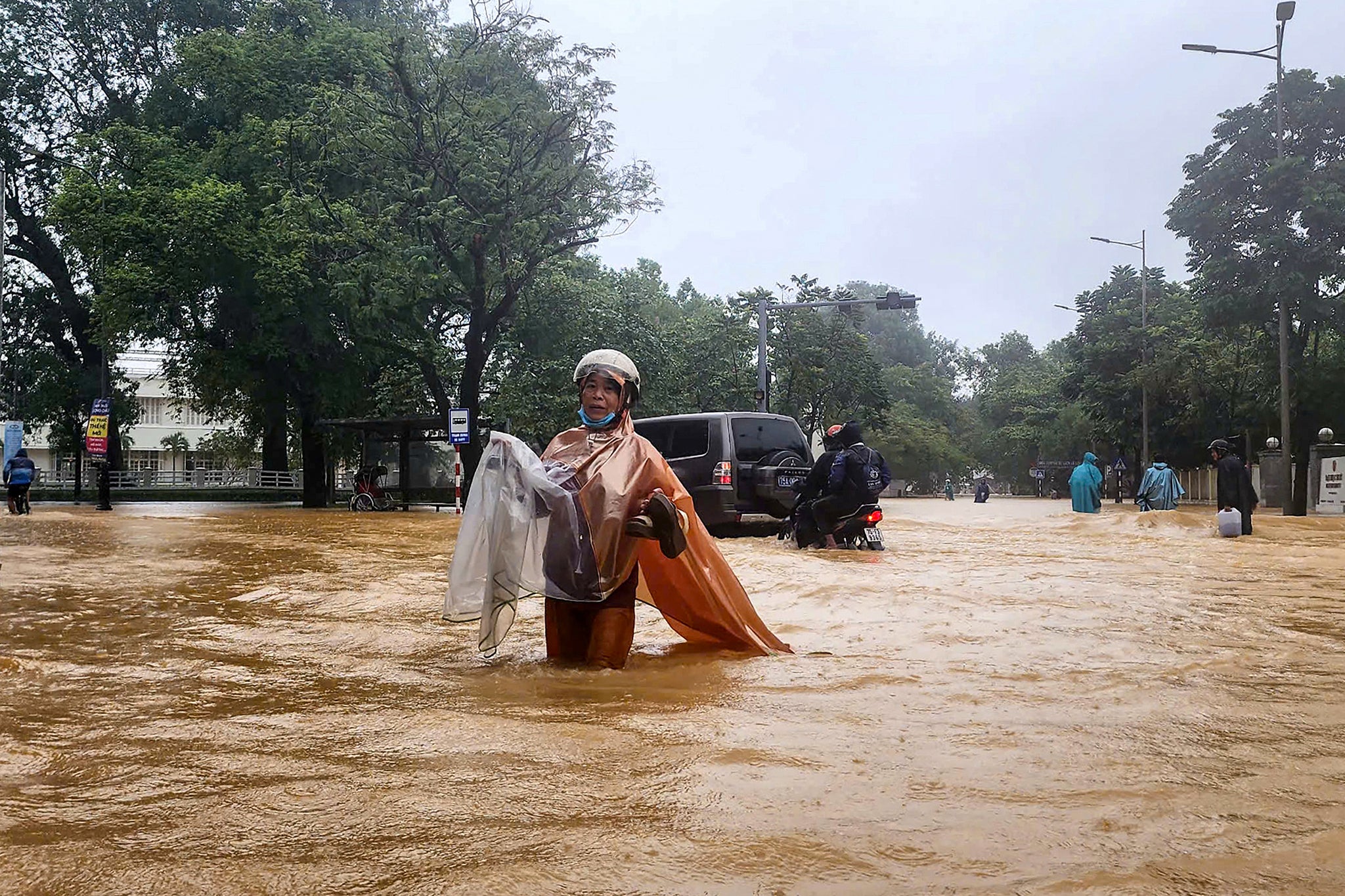 A woman wearing a raincoat wades through a flooded street in Hue, Vietnam