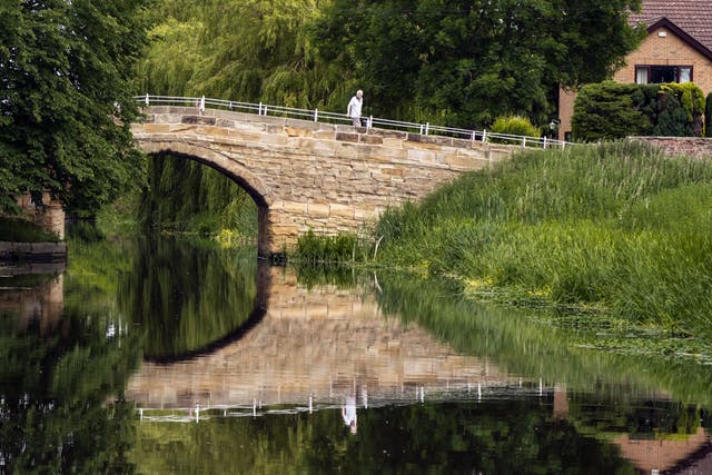 A man crosses a bridge over a tributary to the River Aire in Yorkshire (Danny Lawson/PA)