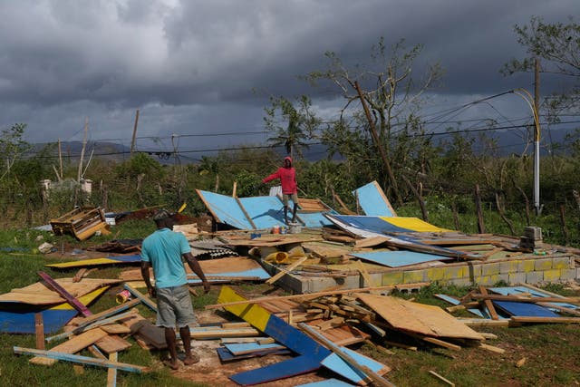Residents stand on the wreckage of a house destroyed by Hurricane Melissa in Santa Cruz, Jamaica (Matias Delacroix/AP)