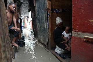 People stay inside a shelter for families displaced by gang violence, flooded by rain brought by Hurricane Melissa, in Port-au-Prince, Haiti