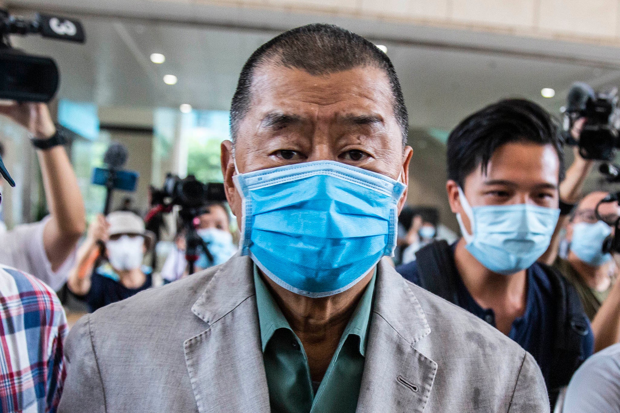 Hong Kong pro-democracy media mogul Jimmy Lai pushes through a media pack as he arrives at the West Kowloon court in Hong Kong
