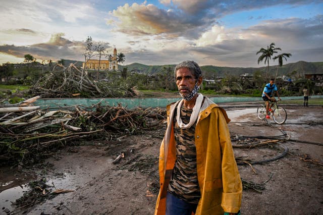 <p>A resident of El Cobre, in the province of Santiago de Cuba, walks past downed trees, power lines and destroyed houses following the passage of Hurricane Melissa, on 29 October</p>