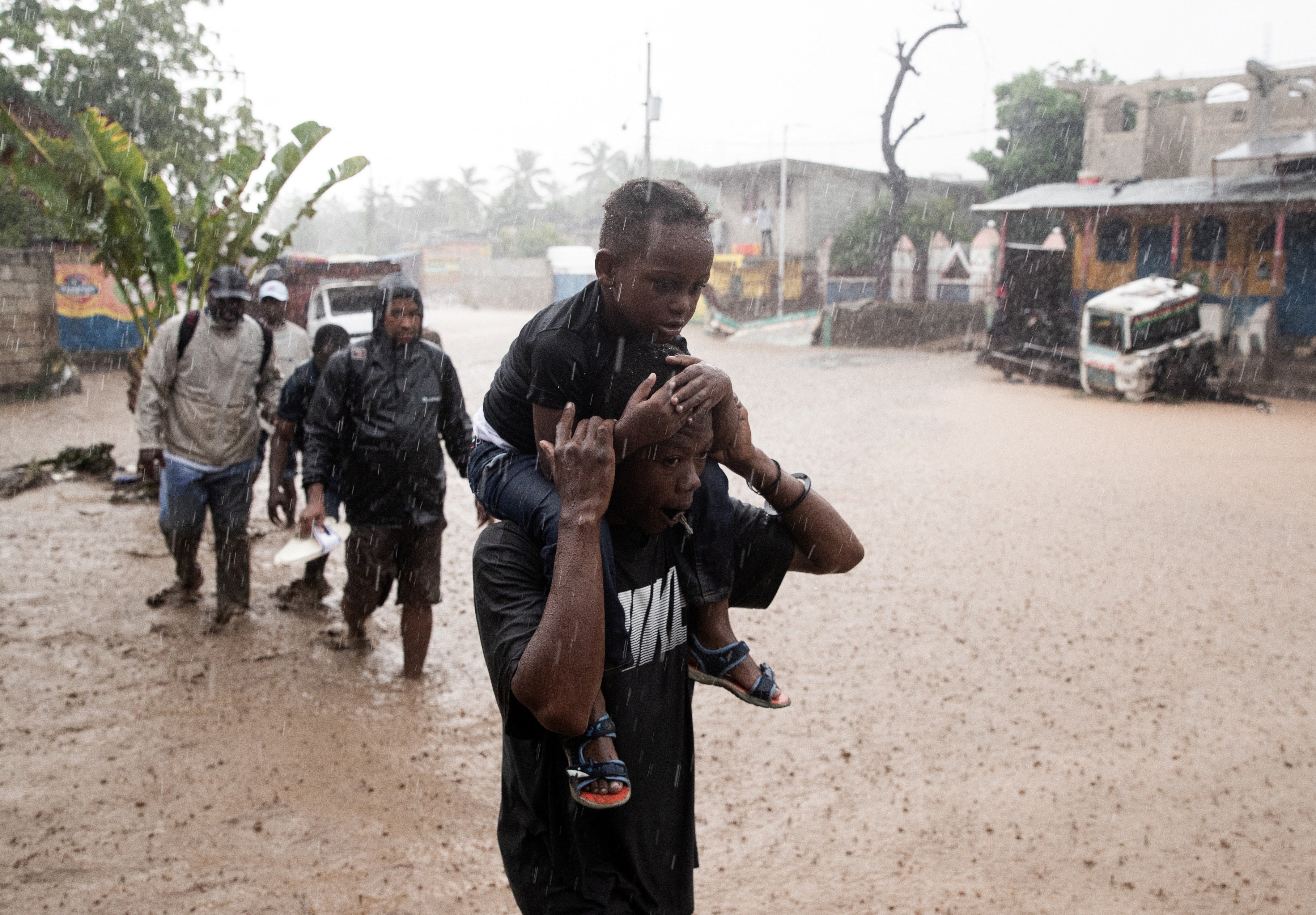 Menschen gehen am Donnerstag in Petit-Goave, Haiti, durch eine überflutete Straße, nachdem Hurrikan Melissa vorbeigezogen ist. Ein Großteil der durch Hurrikane verursachten Schäden ist auf Niederschläge zurückzuführen, da wärmere Atmosphären mehr Feuchtigkeit speichern können