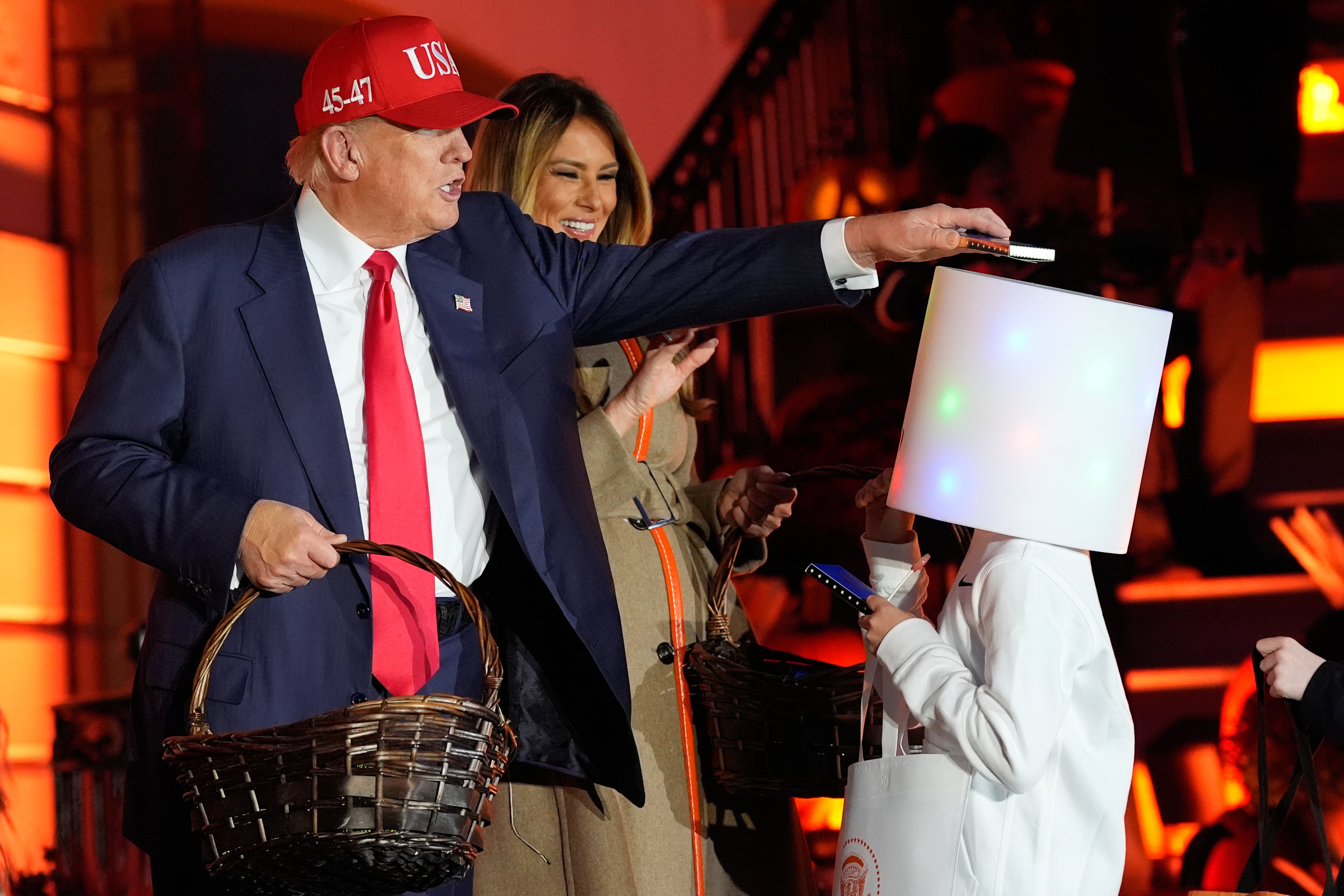 President Donald Trump places a bar of candy on top of a child's costume at the White House Halloween event