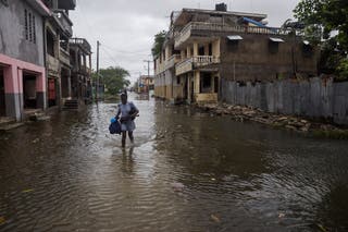 A woman holds her belongings after heavy rains from the outer bands of Hurricane Melissa flooded parts of Les Cayes, Haiti