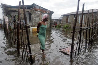 A woman stands outside her home after heavy rains from the outer bands of Hurricane Melissa flooded parts of Les Cayes, Haiti