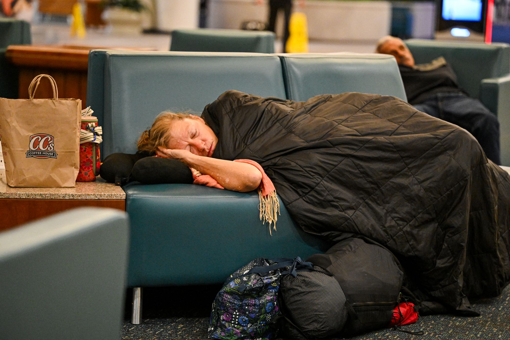 Travellers sleep on chairs at Orlando International Airport in Orlando on October 30