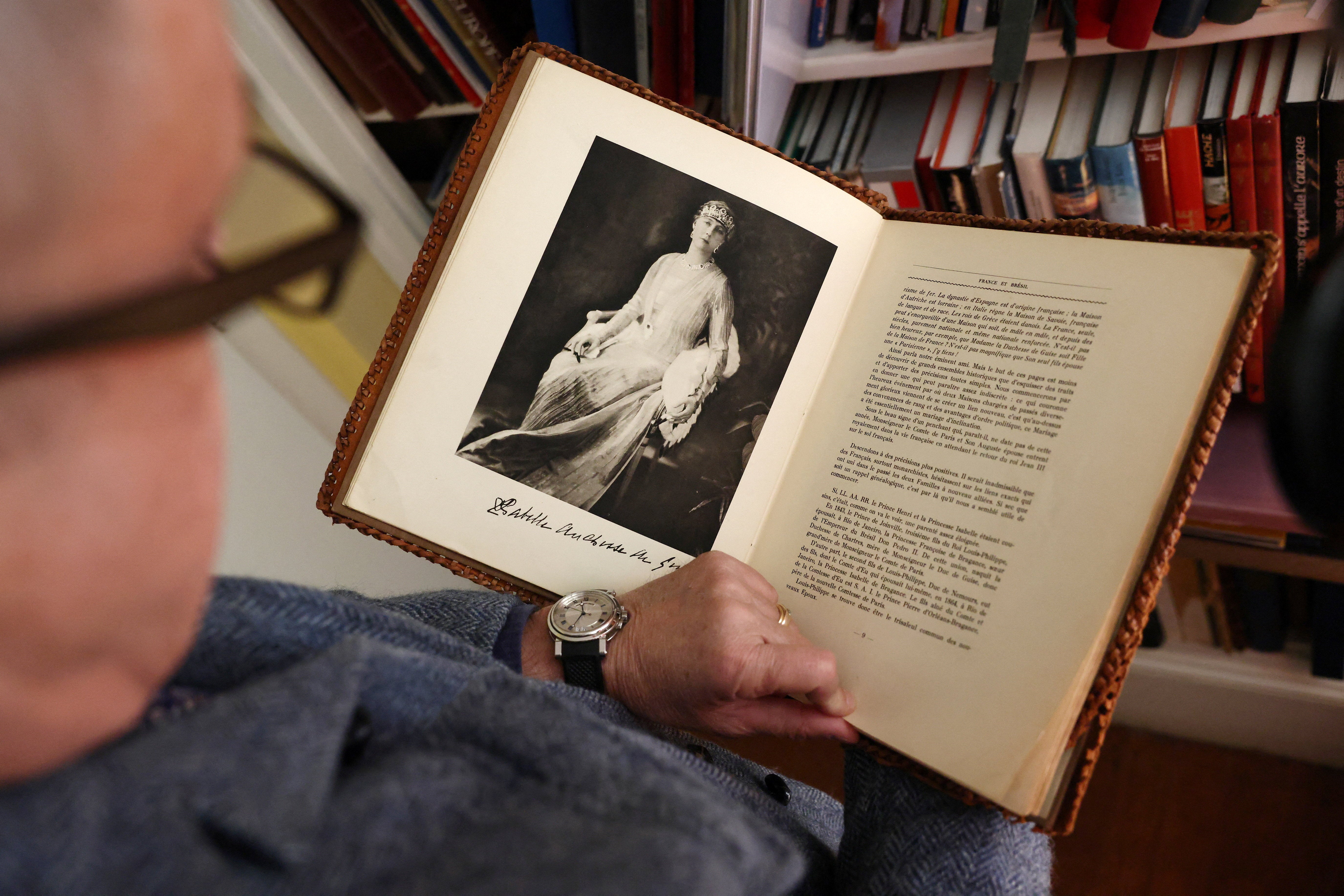 Count of Paris Jean d'Orleans looks at a photo of his great grandmother Marie-Isabelle d'Orleans in a book