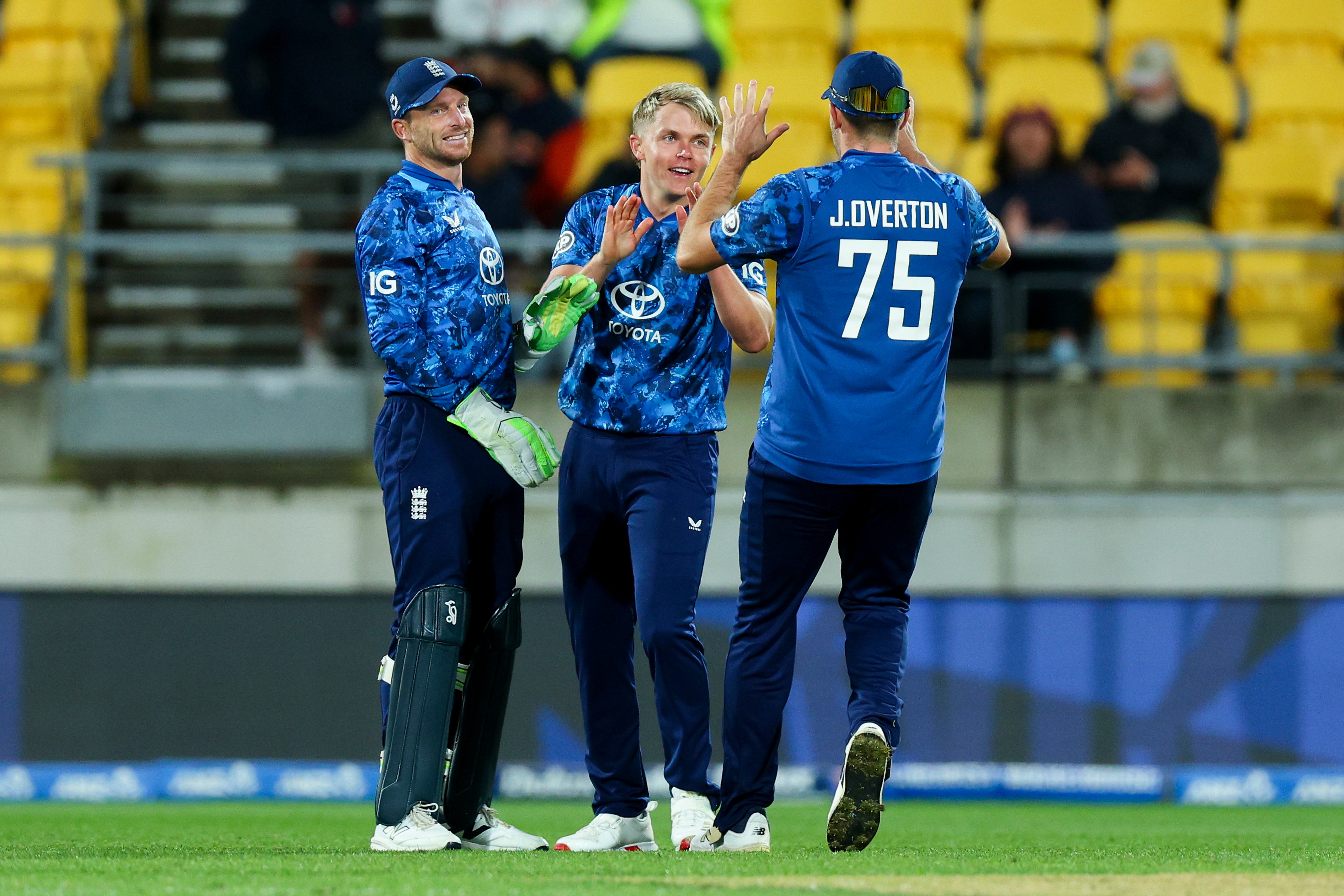 Sam Curran (C) of England celebrates with Jos Buttler (L) and Jamie Overton (R) after taking the wicket of Daryl Mitchell of New Zealand