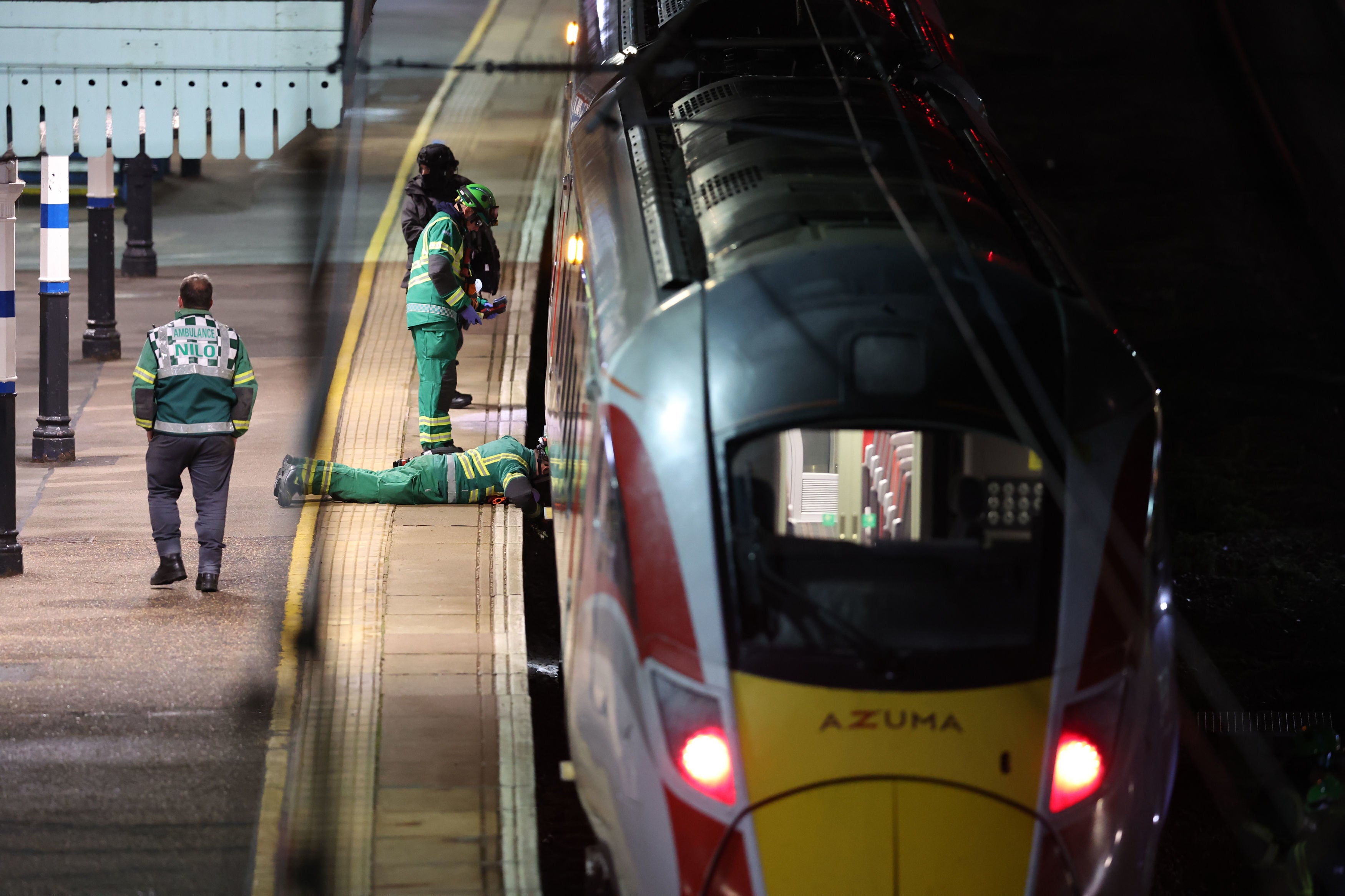 <p>Emergency workers check under the 6.25pm LNER train where the stabbing took place</p>
