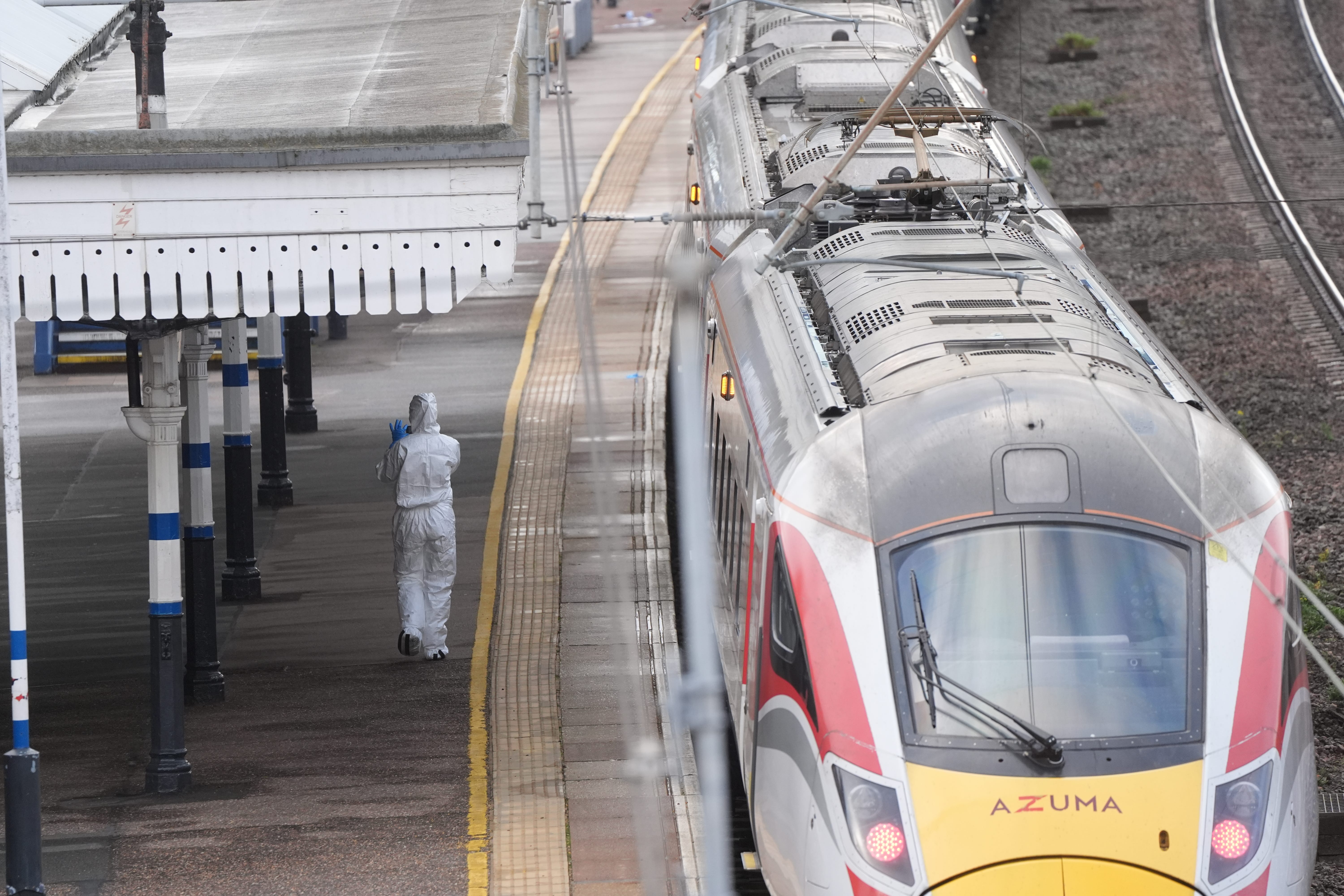 <p>A forensic investigator on the platform by the train at Huntingdon train station (Joe Giddens/PA)</p>