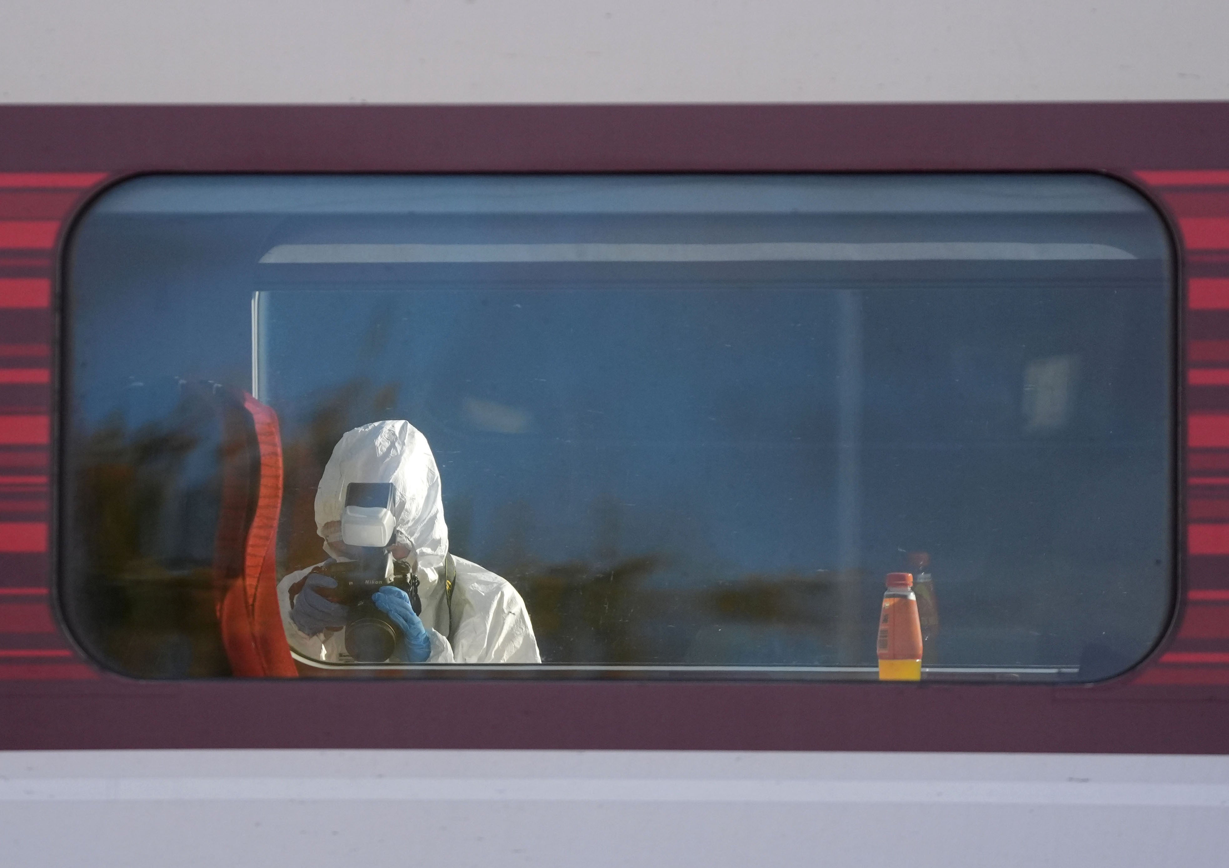 A forensic investigator photographing the scene on the platform by the train at Huntingdon station