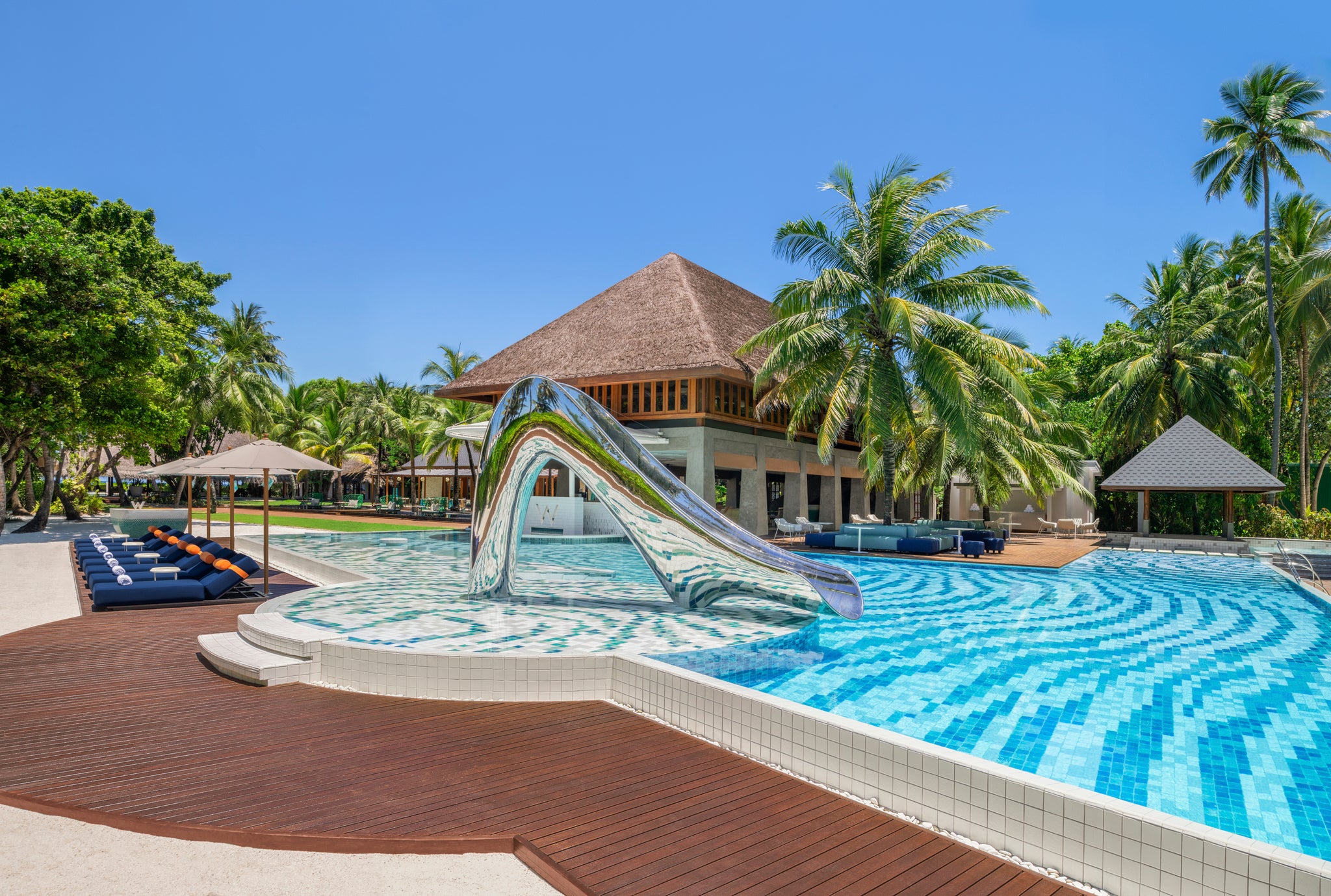 W Maldives’ design is stylish and sleek, with a striking, sculptural water slide in mirror-polished steel standing in the main pool