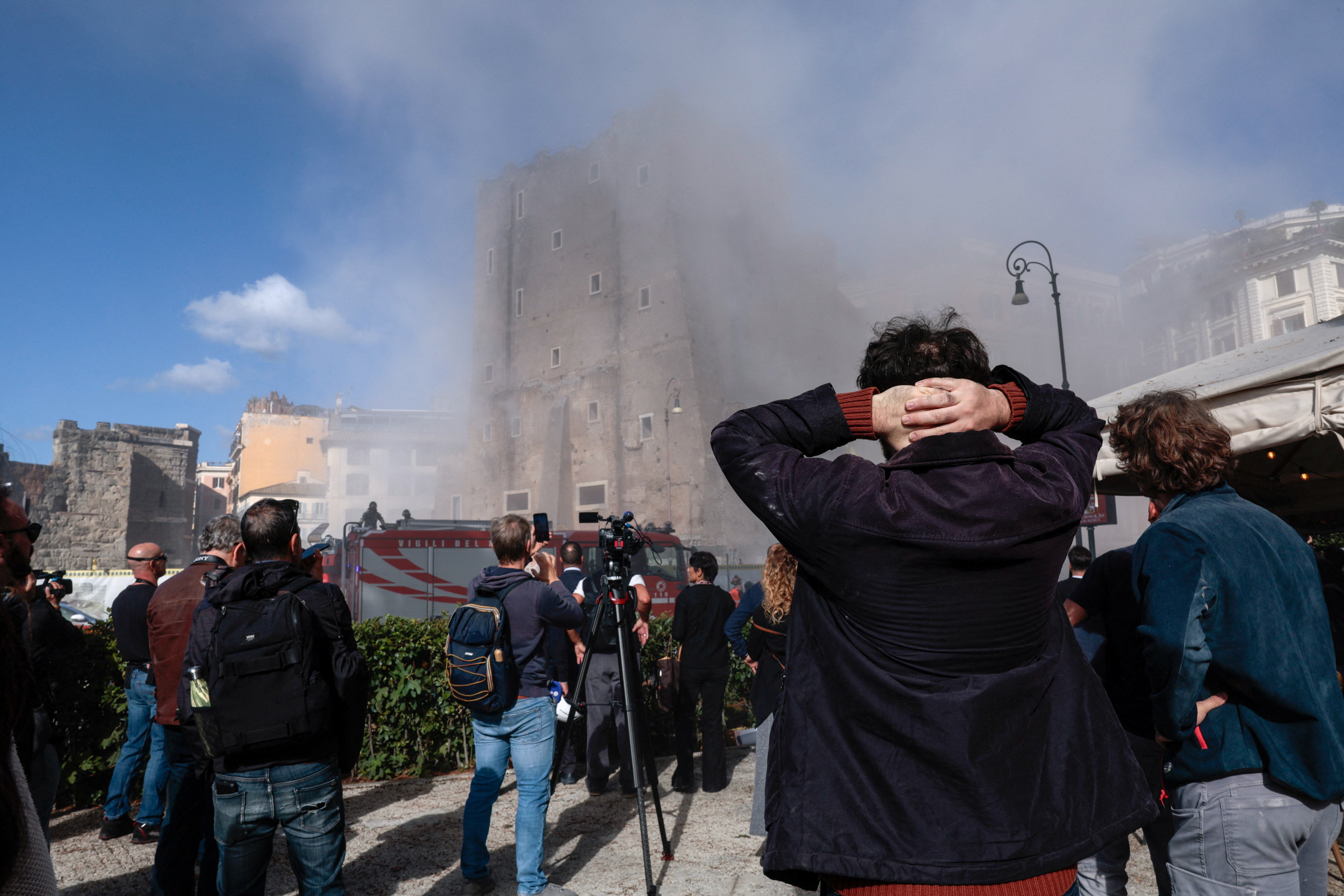 <p>Onlookers watch as dust rises following the collapse of parts of the Torre dei Conti</p>