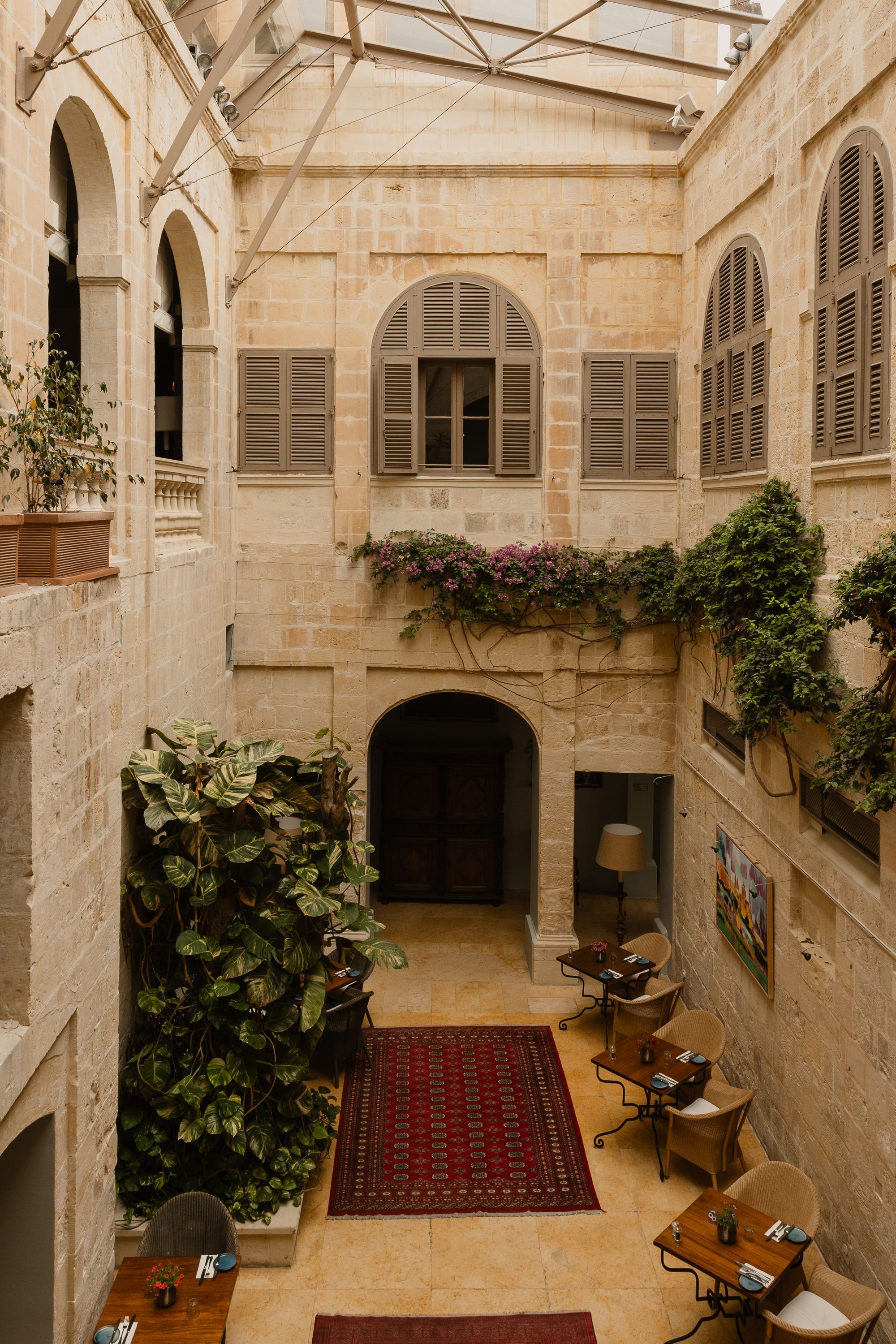 Rugs in a rich red pad the glass-roofed courtyard