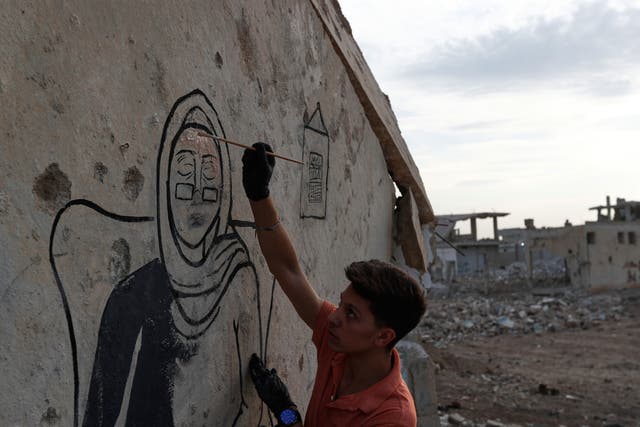 <p>Syrian graffiti artists paint a mural in Daraya, on the outskirts of Damascus, on 3 November 2025</p>
