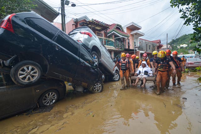 <p>Rescuers carry a resident past cars washed away by floods at the height of Typhoon Kalmaegi</p>