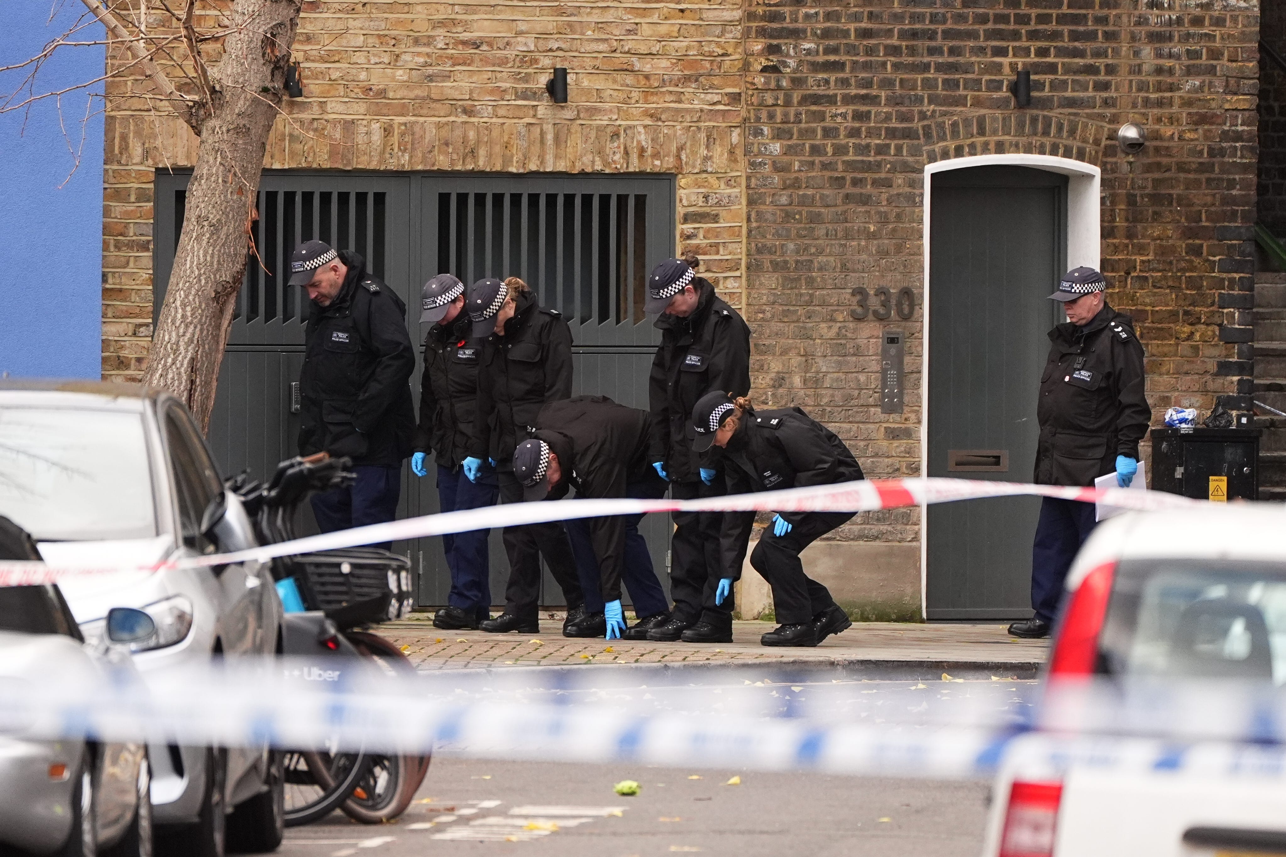Police officers searching the scene of the shooting on Southern Grove in Ladbroke Grove (PA)
