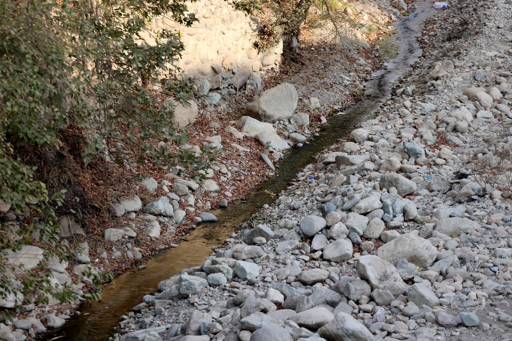 <p>A trickle of water flows in the mainly dried-up Kan River, west of Tehran, on 9 November</p>