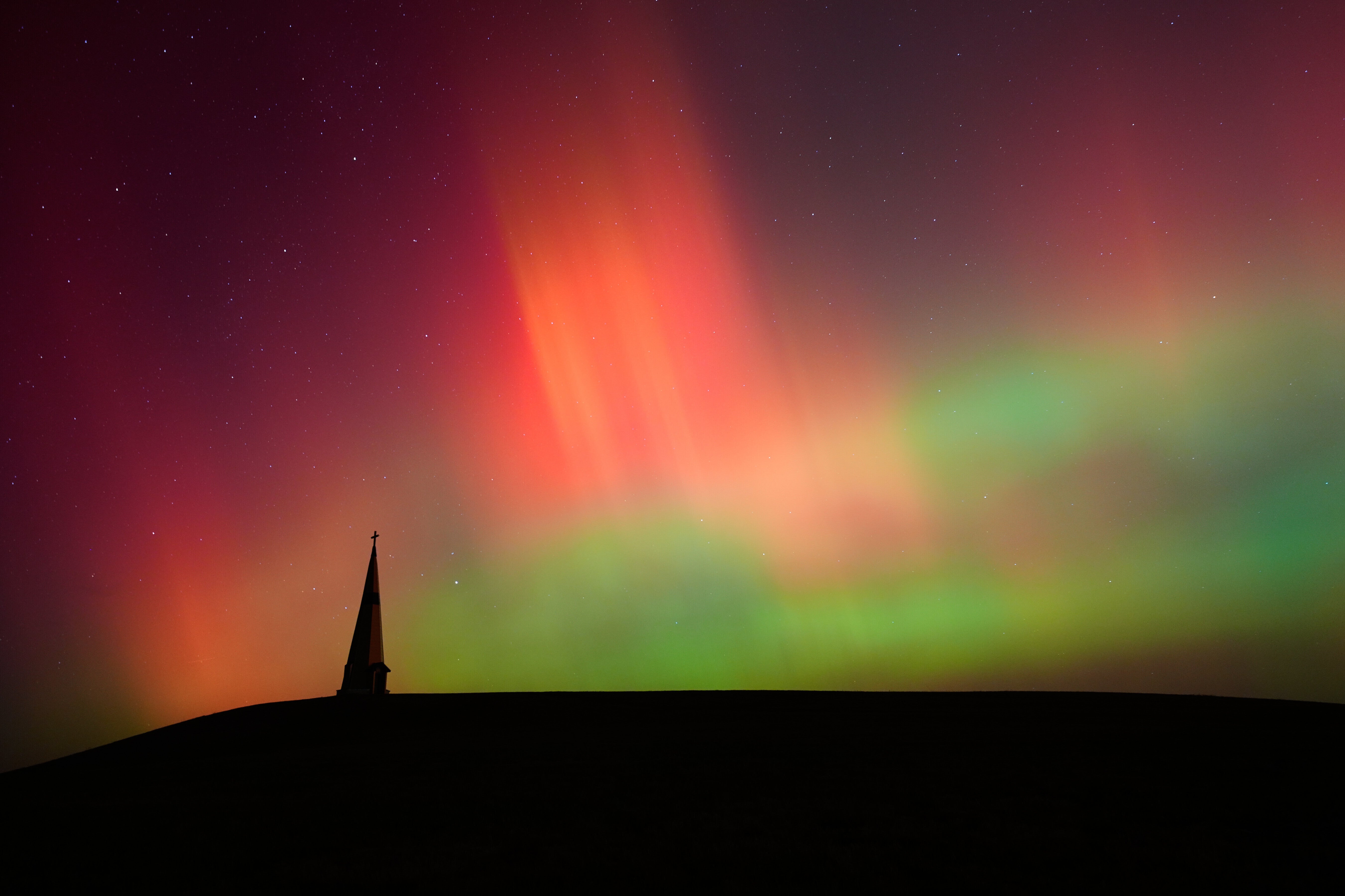 The northern lights fill the sky behind the Saint Joseph the Woodworker Shrine Tuesday, Nov. 11, 2025, near Valley Falls, Kan.