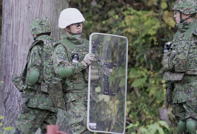<p>A member of Japan Self-Defence Forces holds a shield during a practice setting up a bear trap </p>