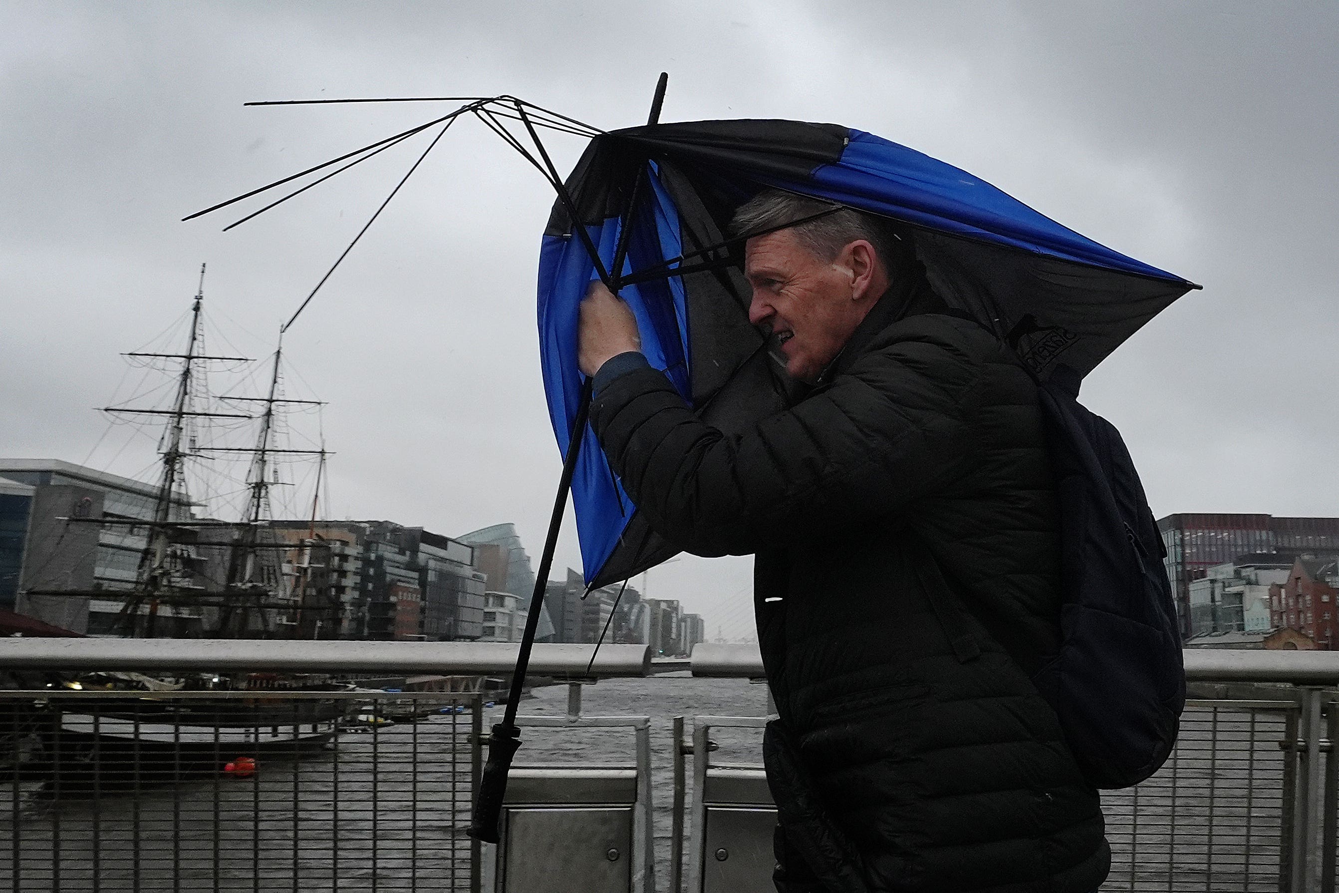 A person holding an umbrella crosses the Sean O’Casey bridge during a wet and windy afternoon in Dublin as a Status Orange rain warning comes into effect as a result of Storm Claudia (Brian Lawless/PA)