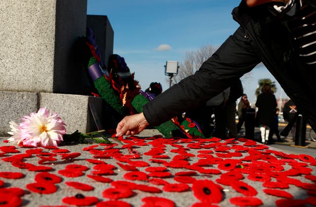 <p>People place poppies at the base of the cenotaph during the Remembrance Day ceremony at the legislature in Victoria, British Columbia, Canada, Tuesday, 11 November 2025. (Chad Hipolito/The Canadian Press via AP)</p>