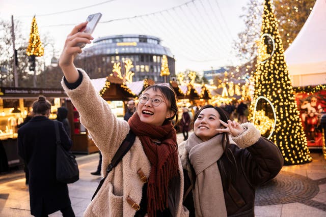<p>Tourists from China pose for a selfie as they visit the annual Christmas market at Breitscheidplatz in the city center on November 26, 2024 in Berlin, Germany</p>