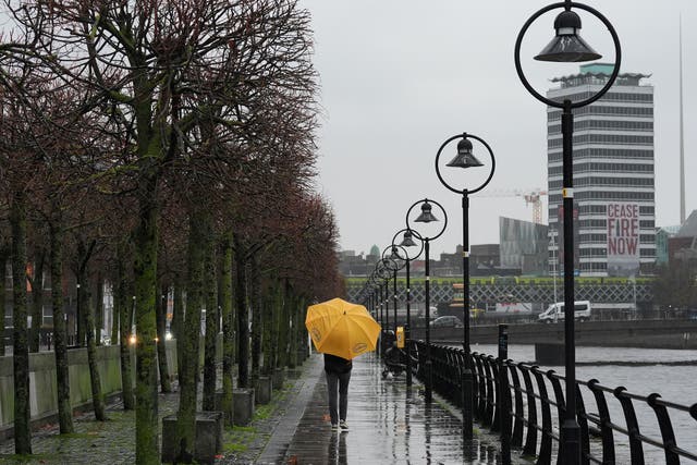 A person holding an umbrella walks along the quays on a wet and windy afternoon in Dublin as a Status Orange rain warning comes into effect as a result of Storm Claudia. Picture date: Friday November 14, 2025.