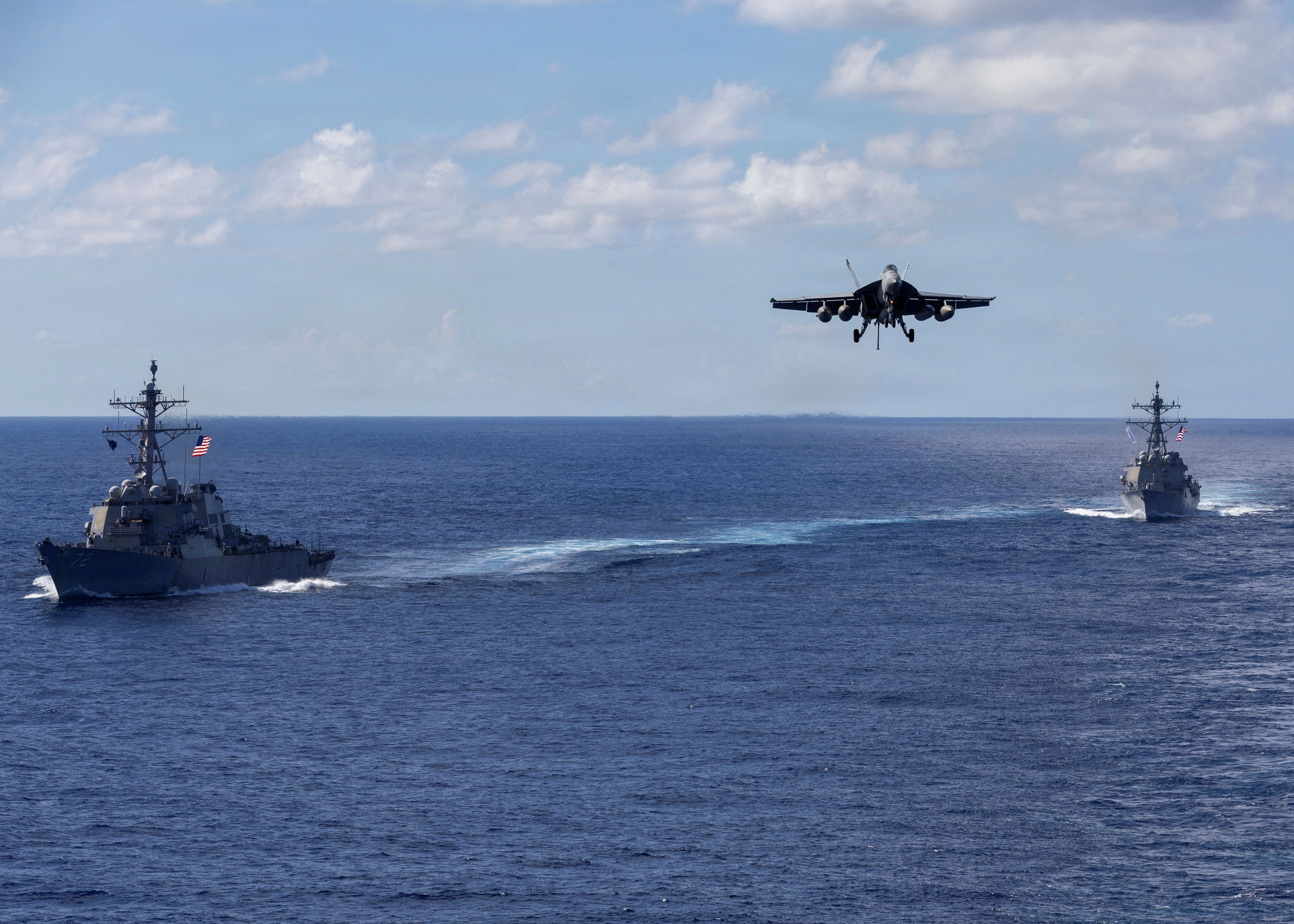 The guided-missile destroyers USS Mahan, left, and USS Bainbridge sailing in formation as an F/A-18 Super Hornet descends on final approach to land on the aircraft carrier USS Gerald R. Ford, which has moved to the Caribbean to join the U.S. military buildup near Venezuela