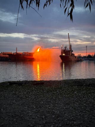 From the Romanian side of the border on the Danube, a Ukrainian vessel sprays water on a cargo ship engulfed by flames following Russian strikes