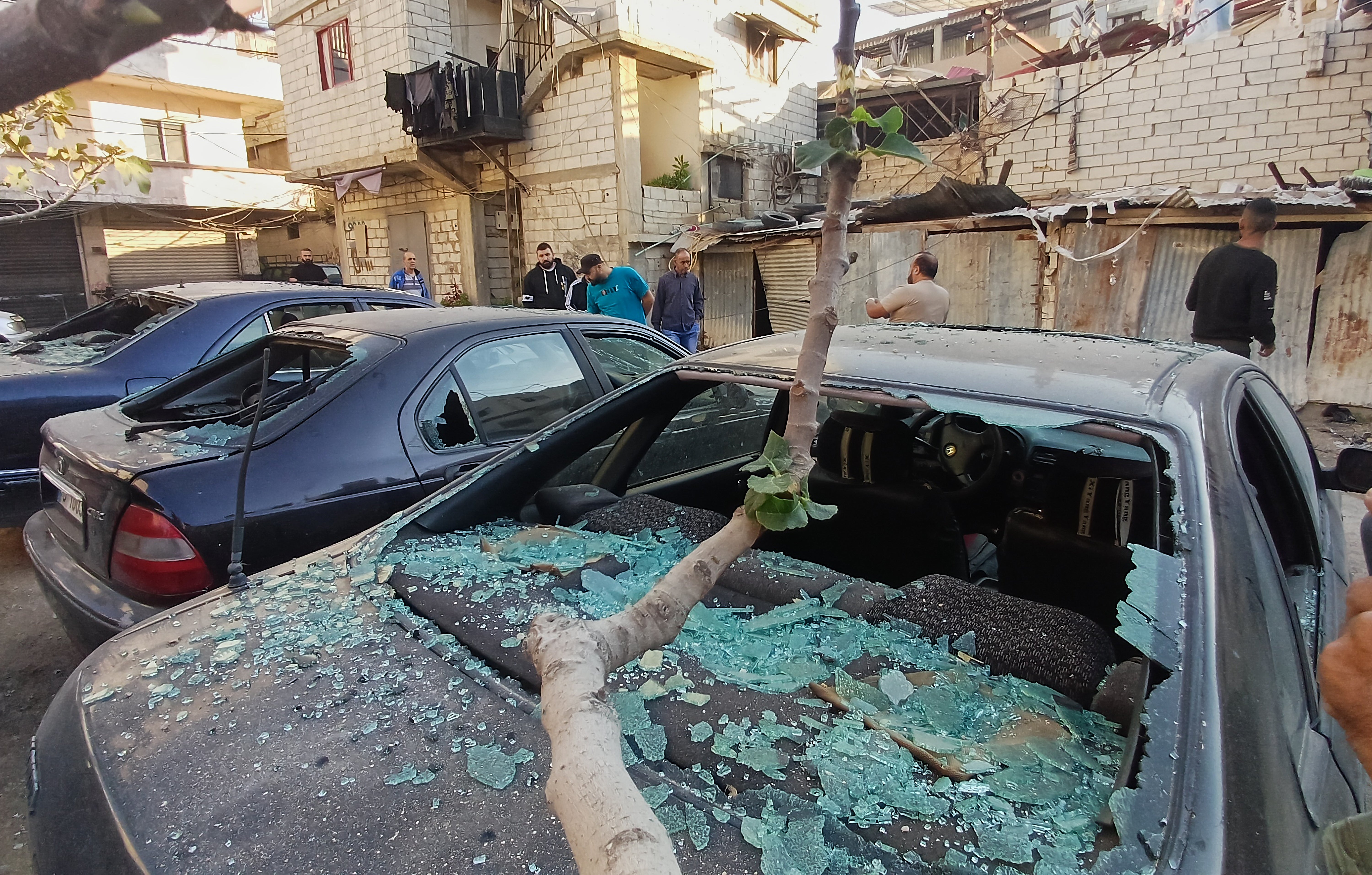 <p>Palestinians people check cars damaged by an Israeli attack on Ain al-Hilweh refugee camp in southern Lebanon</p>