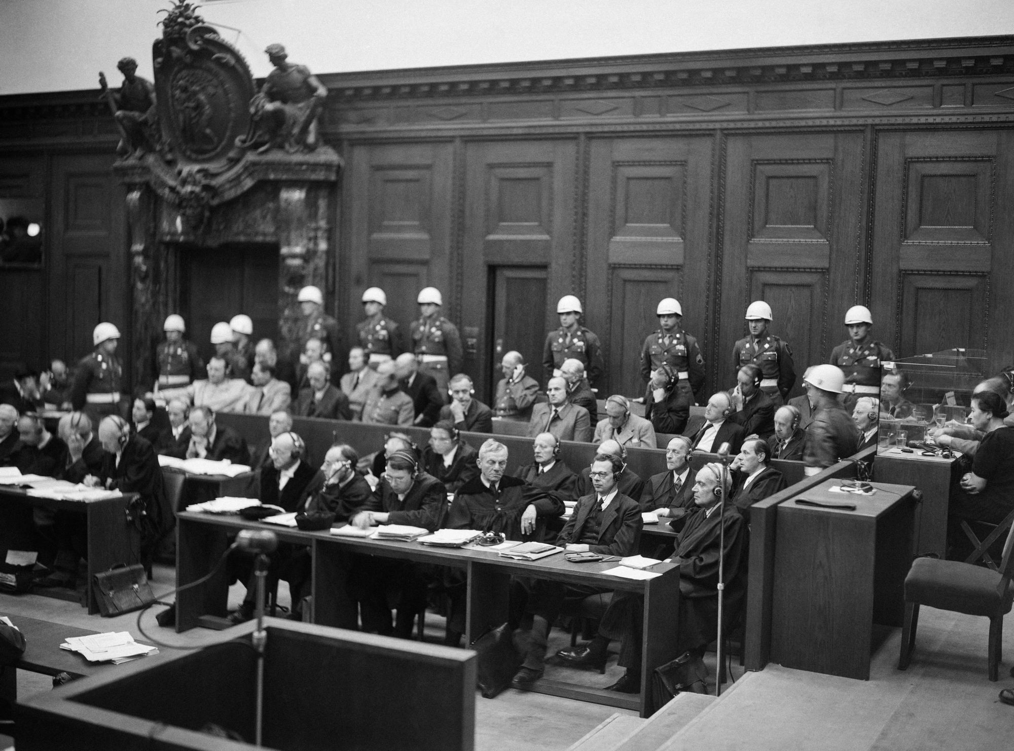 The defendants sit on their bench surrounded by police officers in the law court of Nuremberg on 20 November 1945