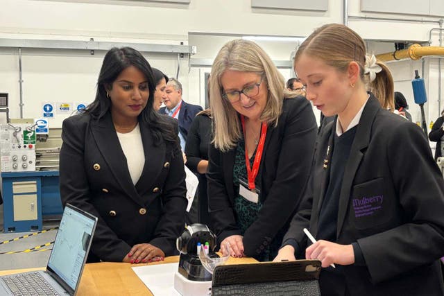Skills minister Baroness Jacqui Smith, centre, and MP Uma Kumaran are shown a robot by a pupil at Mulberry UTC in east London (PA)